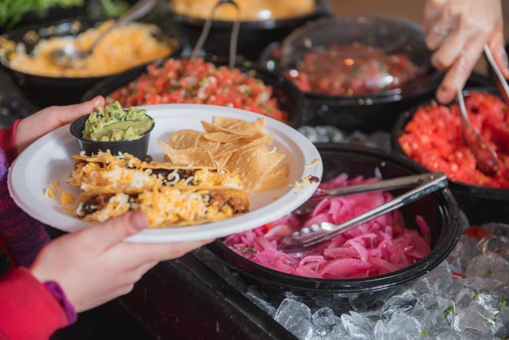 Hungry customers serving food from Tower7 Restaurant Catering spread.