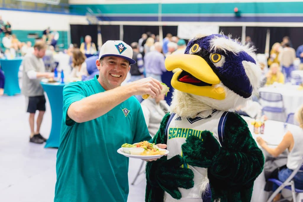 A sports fan enjoying Tower7 Catering with their team mascot, a SeaHawk